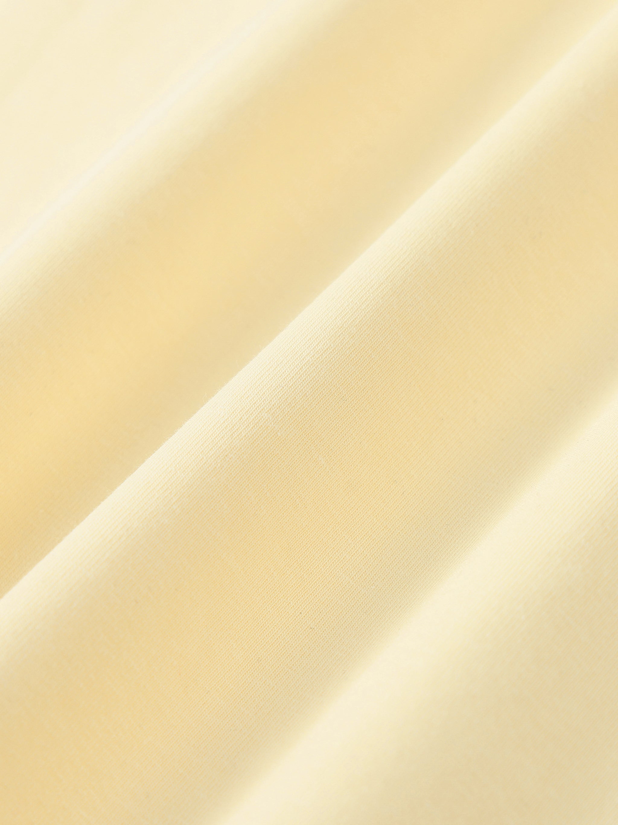 Close-up of soft cream yellow heavyweight cotton fabric with subtle texture and draping folds