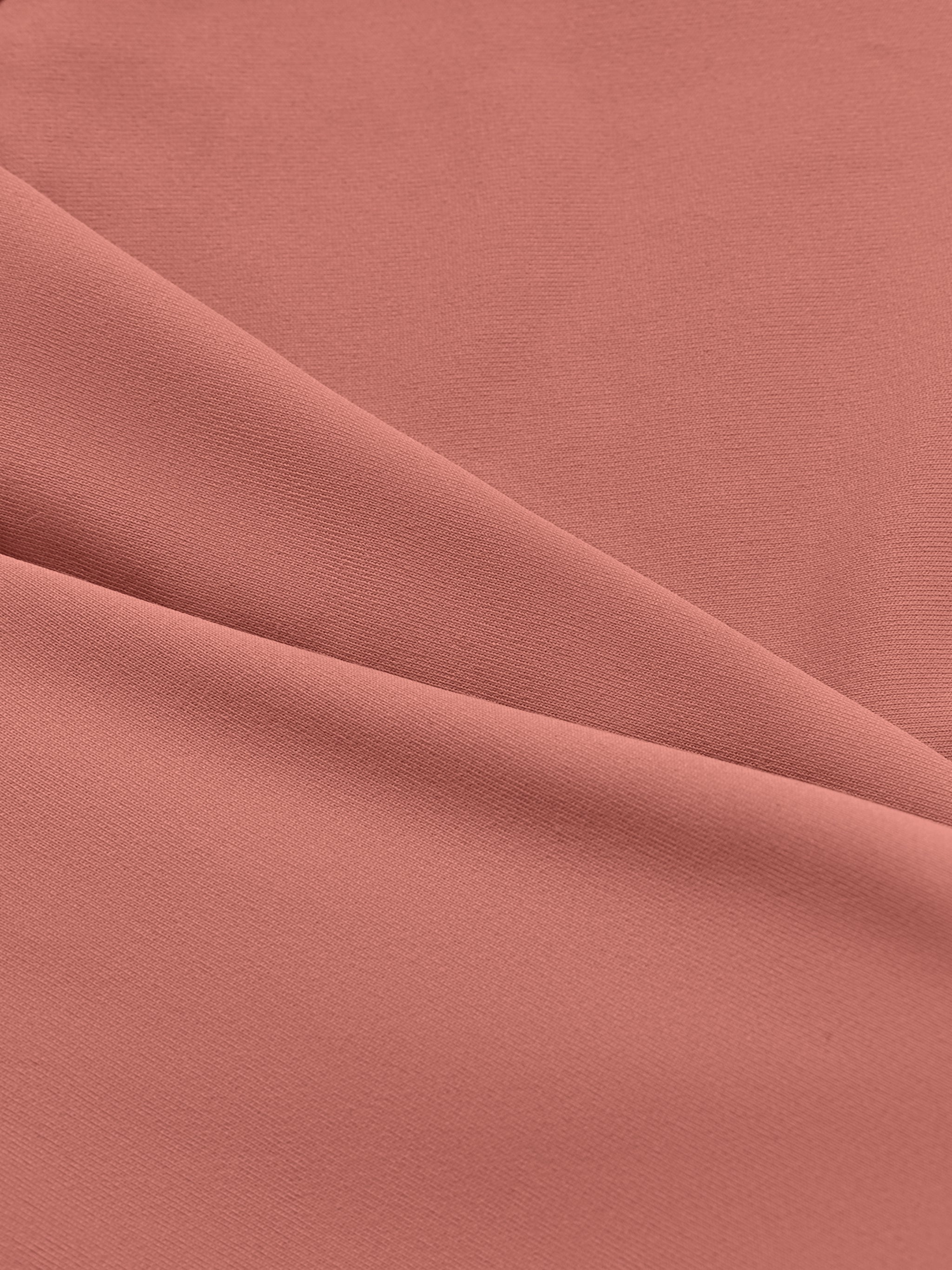 Close-up of soft, stretchy pink sports bra fabric with smooth texture and gentle folds.