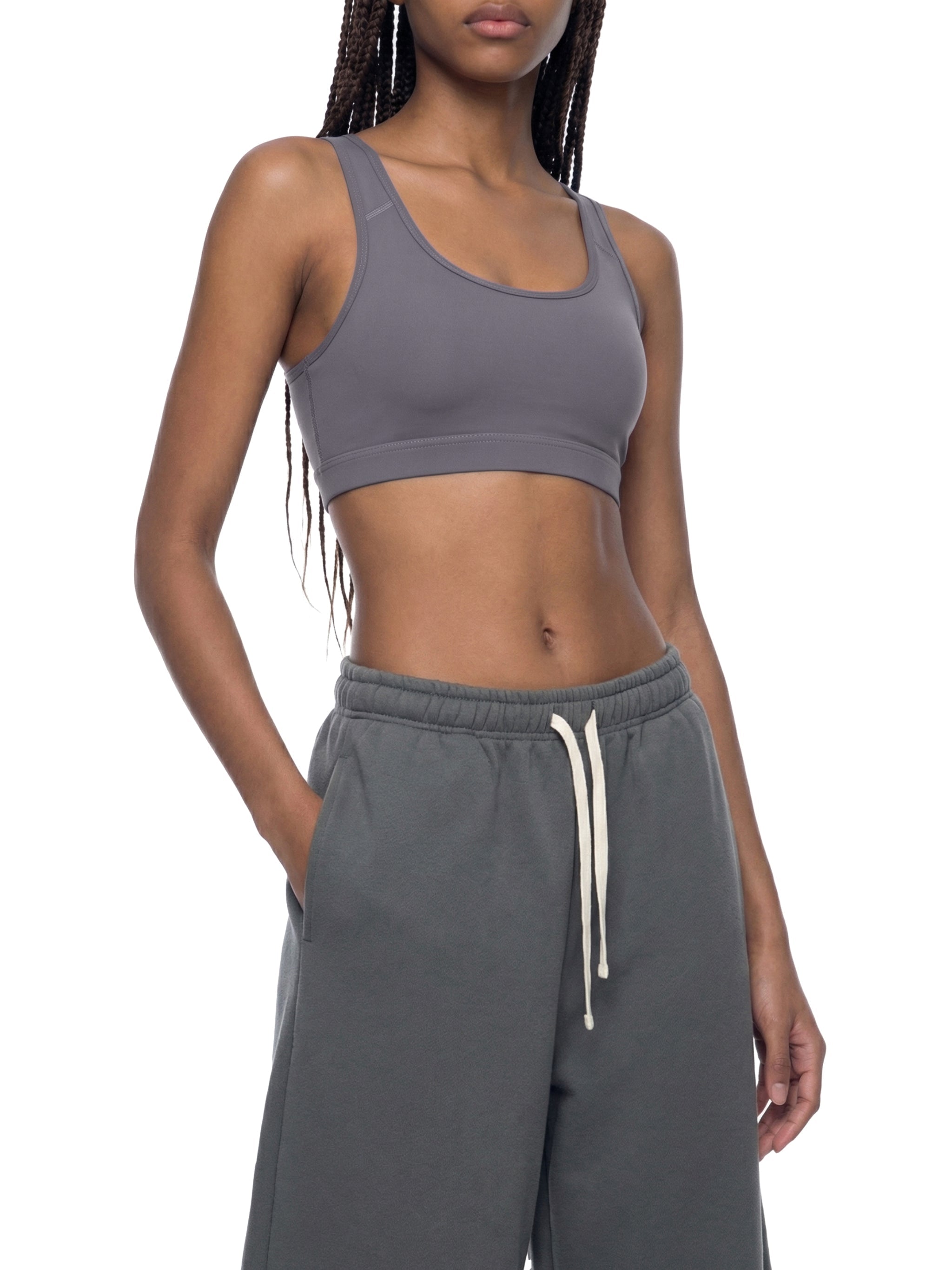 Woman wearing grey cropped sports bra and drawstring sweatpants, streetwear style
