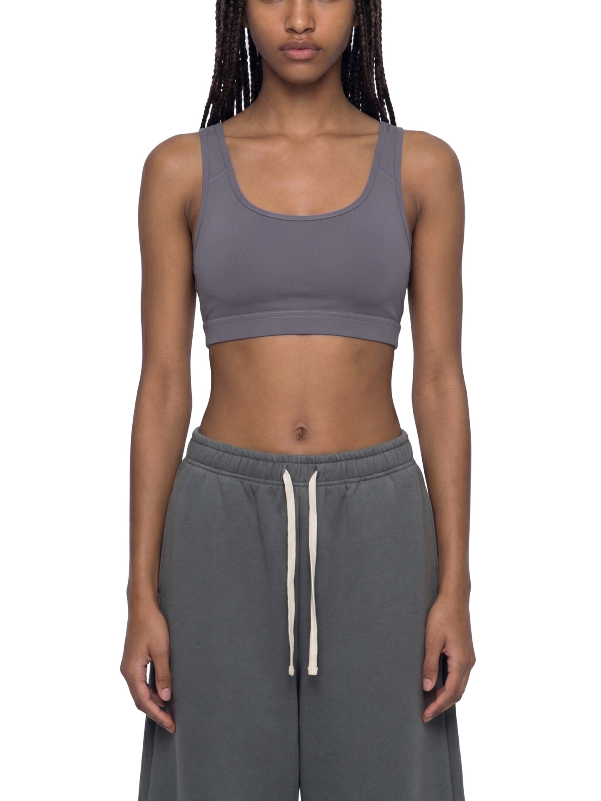 Woman wearing a grey cropped sports bra and matching sweatpants, front view
