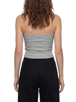 Back view of woman wearing a gray cropped tube top and black pants on white background