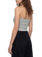 Woman wearing gray cropped tube top and black high-waisted pants, back view