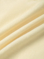 Close-up of soft, heavyweight cream knit fabric with textured surface and natural folds