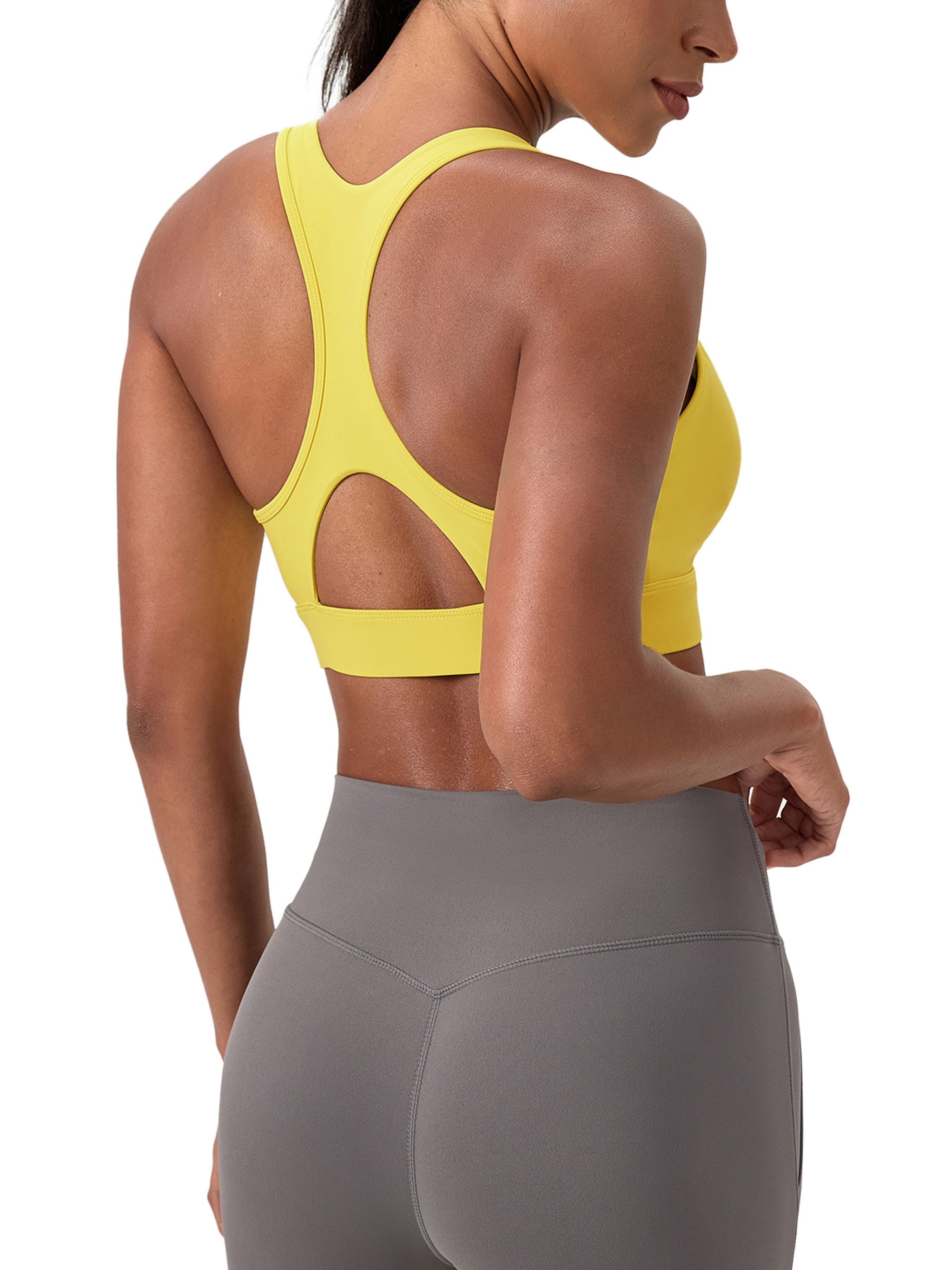 Woman wearing yellow sports bra with racerback and gray high-waisted leggings