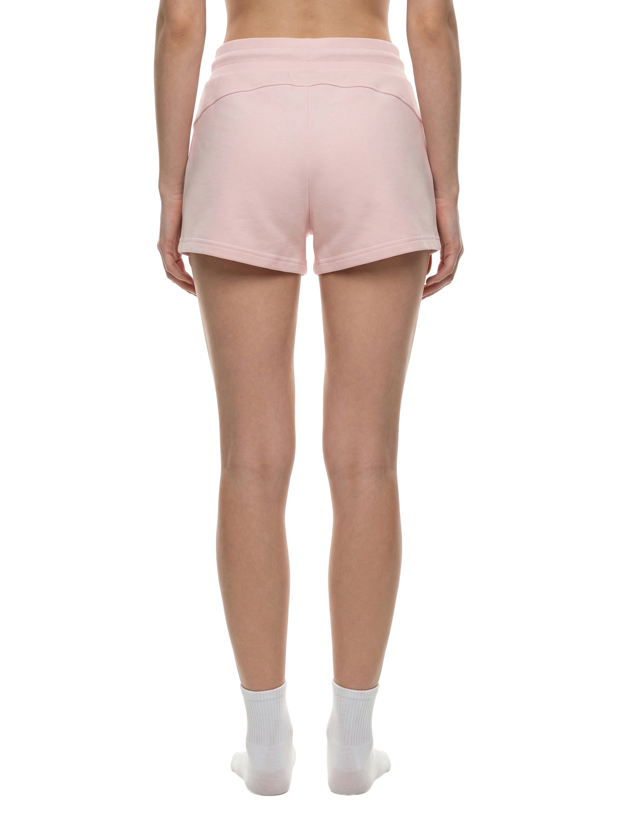 Back view of a woman wearing light pink drawstring shorts and white ankle socks