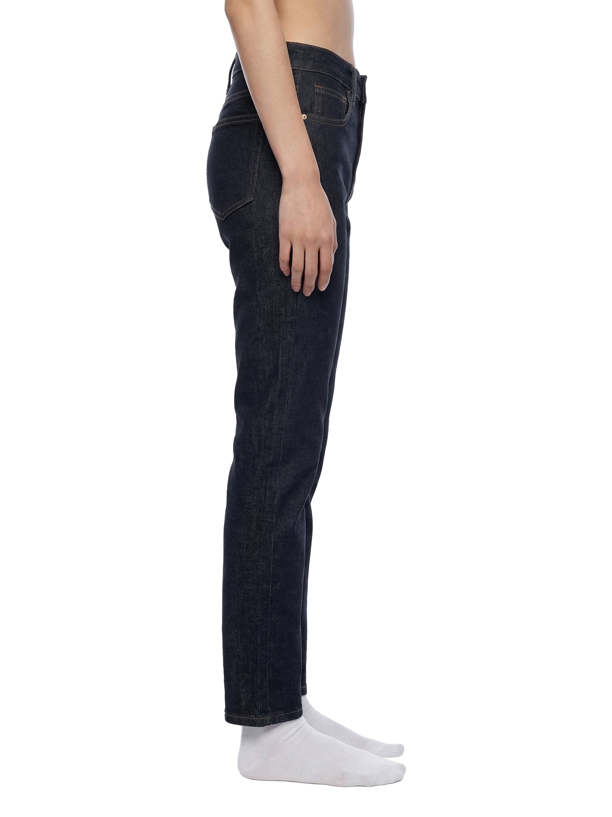 Side view of woman wearing high-rise skinny jeans in dark denim on white background