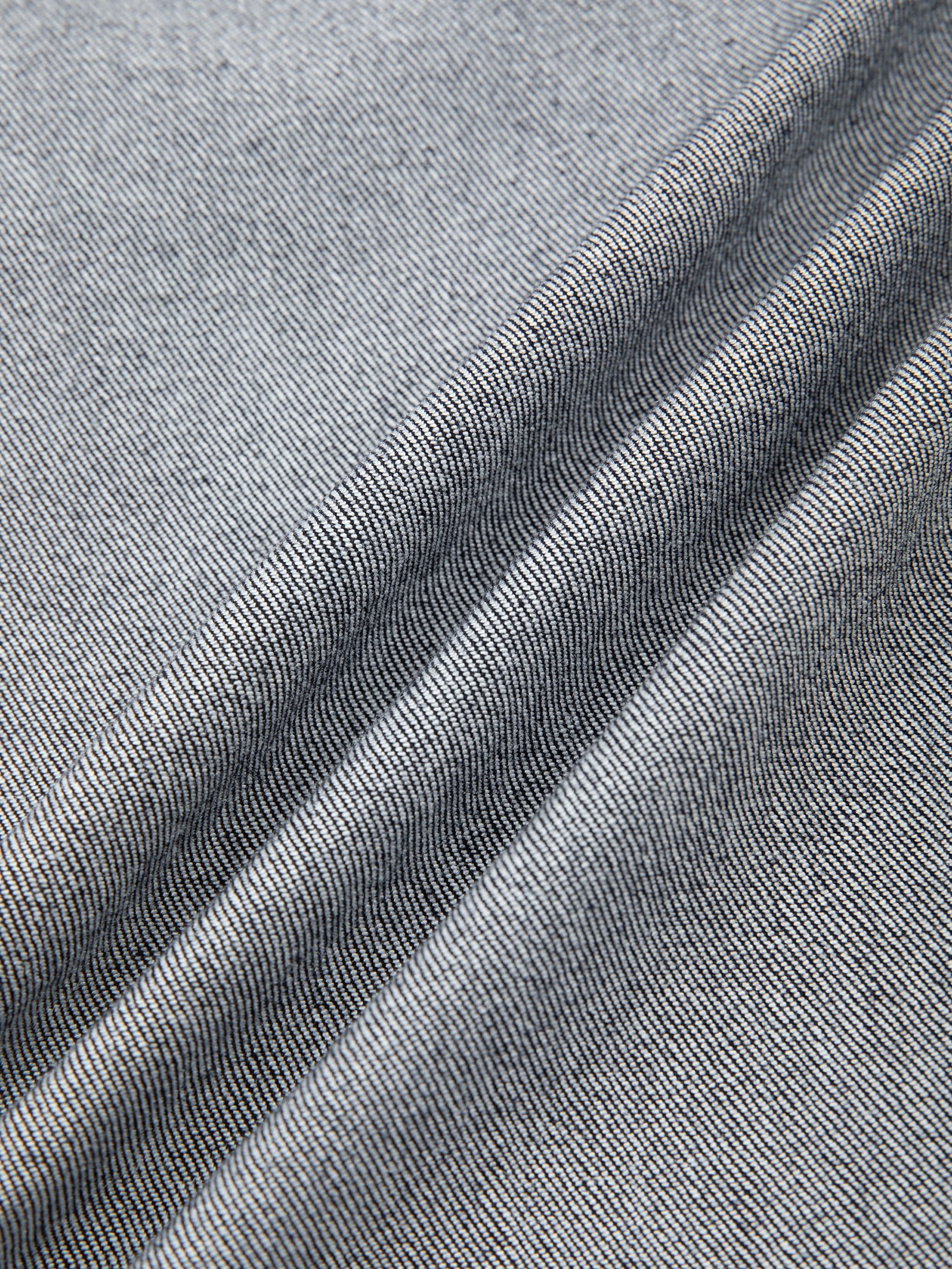 Close-up of light blue denim fabric texture with fine weave and soft folds