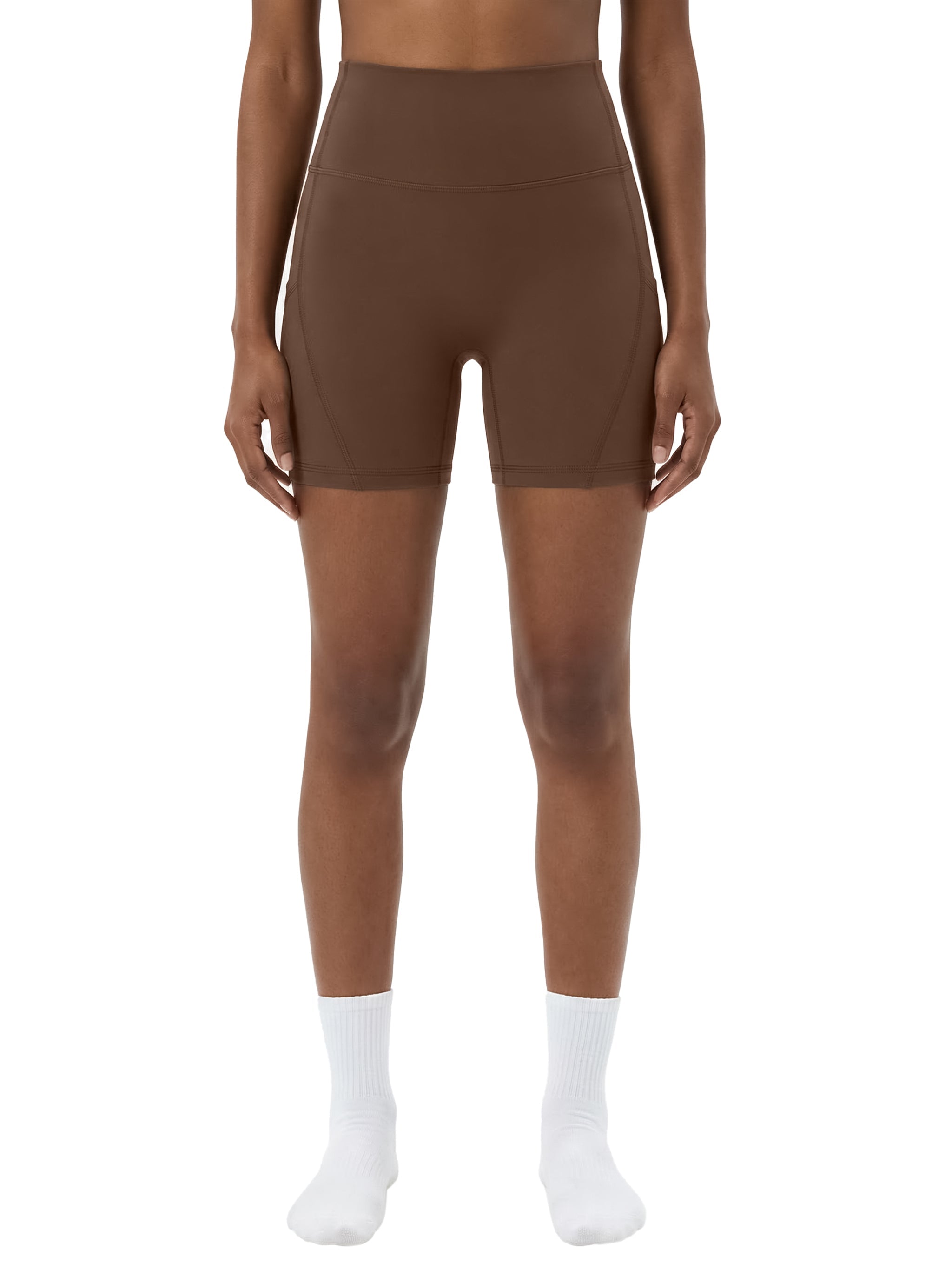 Woman wearing brown high-waisted biker shorts with pockets against a white background