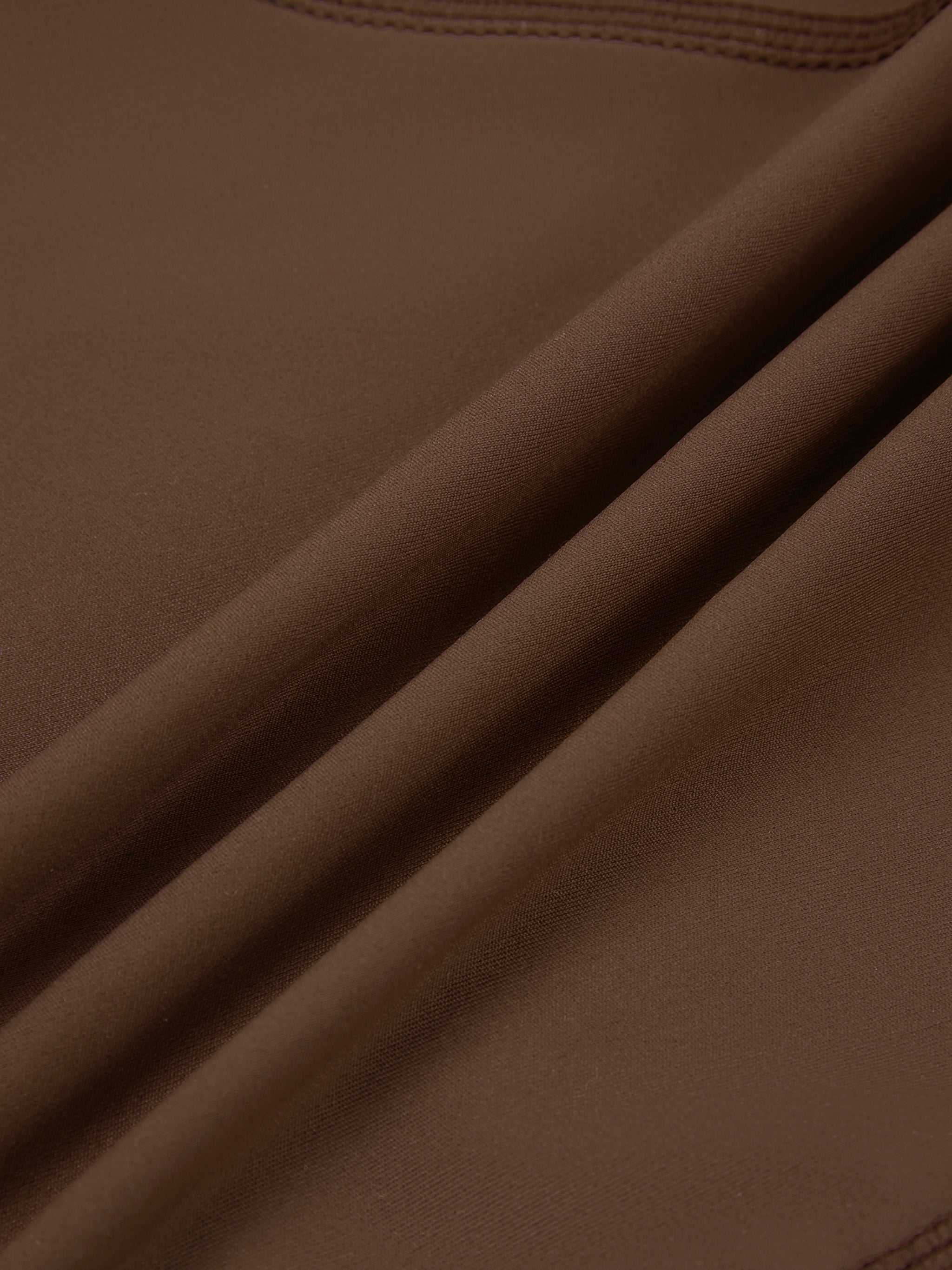 Close-up of brown high-waisted biker shorts fabric with visible stitching and texture