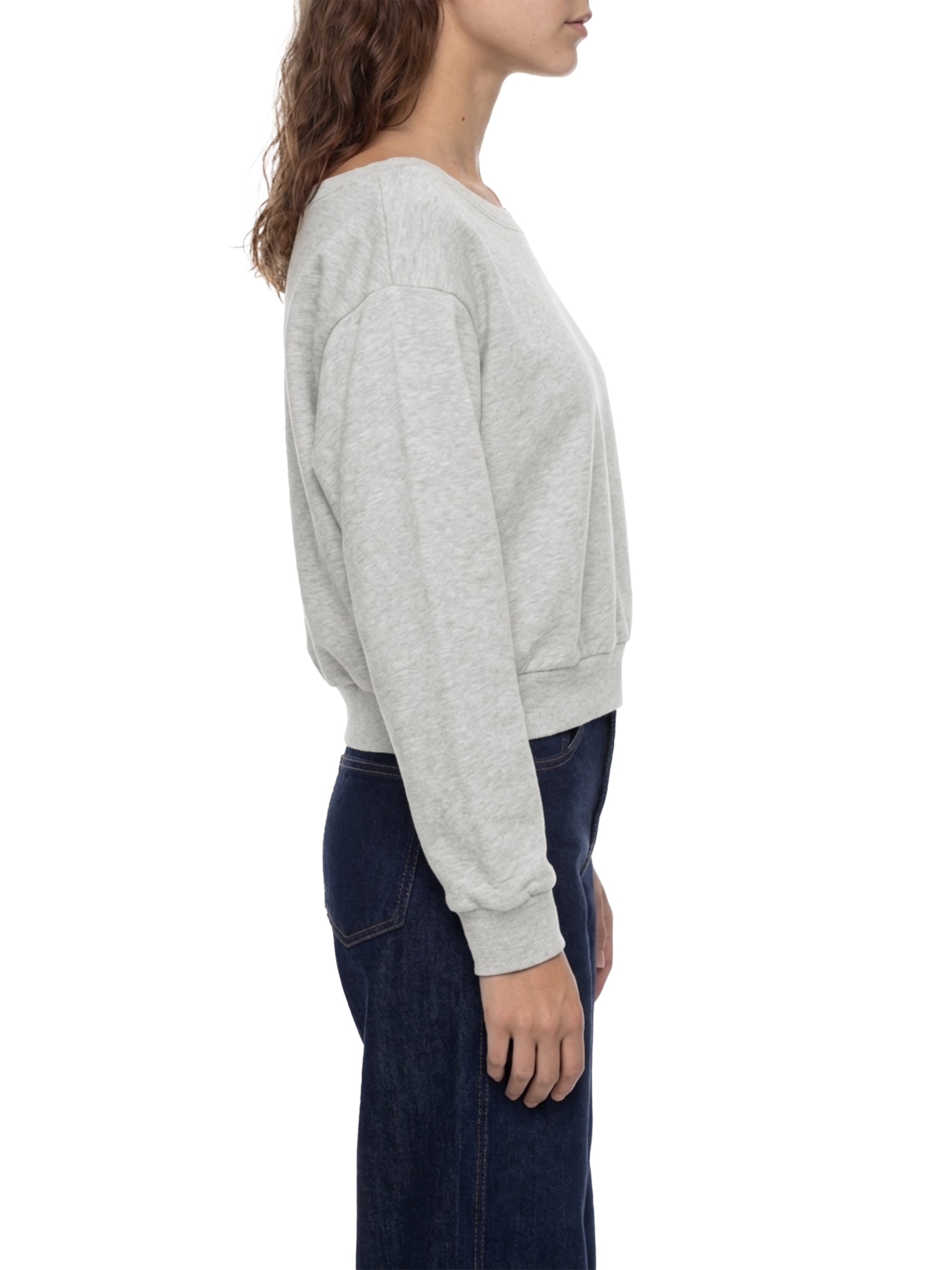 Woman in light gray off-shoulder sweatshirt and dark jeans, side profile, white background