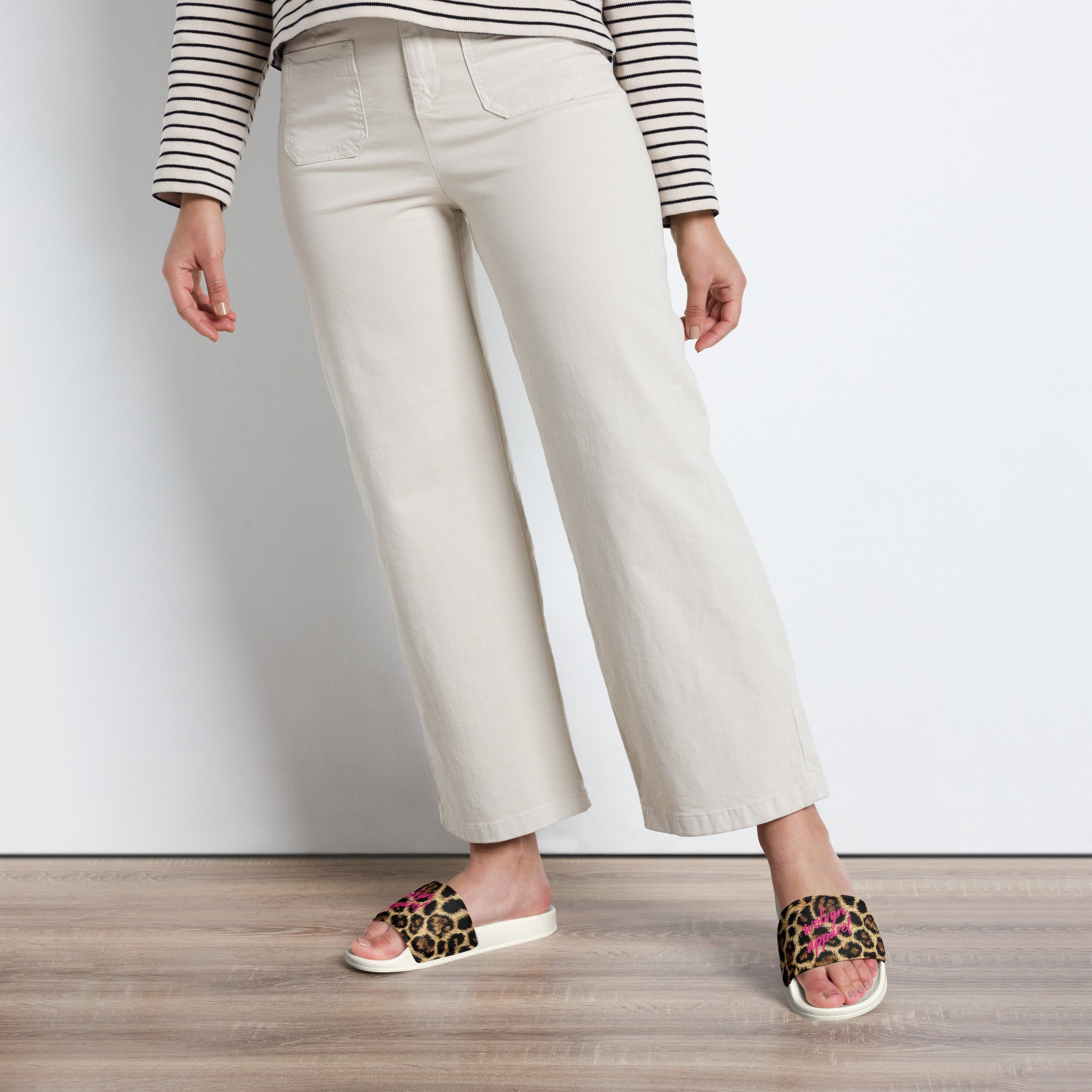 Woman wearing cream wide-leg pants and leopard print slides on wooden floor