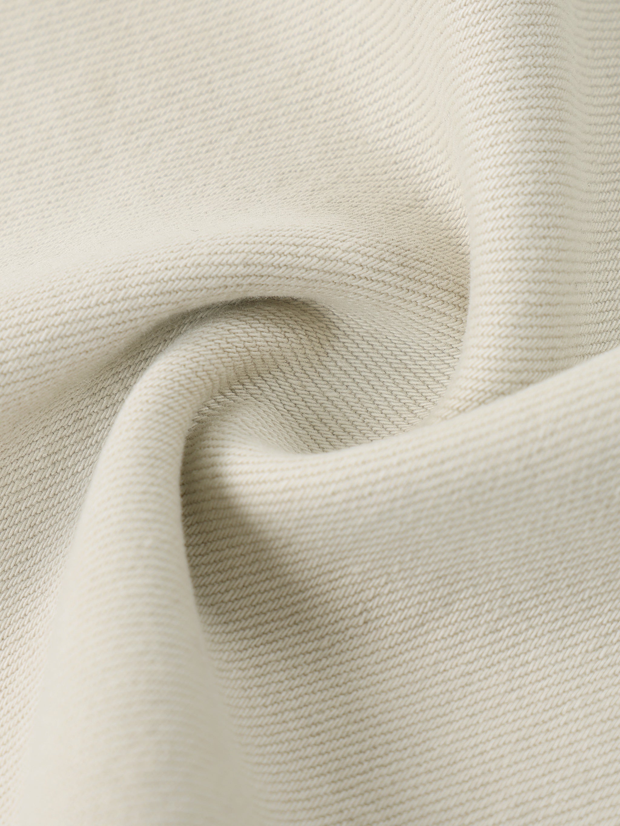 Close-up of beige denim fabric with visible texture and weave details.