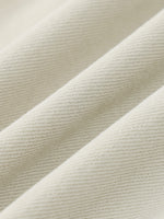 Close-up of cream-colored denim fabric with visible twill texture and soft folds