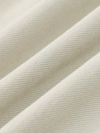 Close-up of cream-colored denim fabric with visible twill texture and soft folds