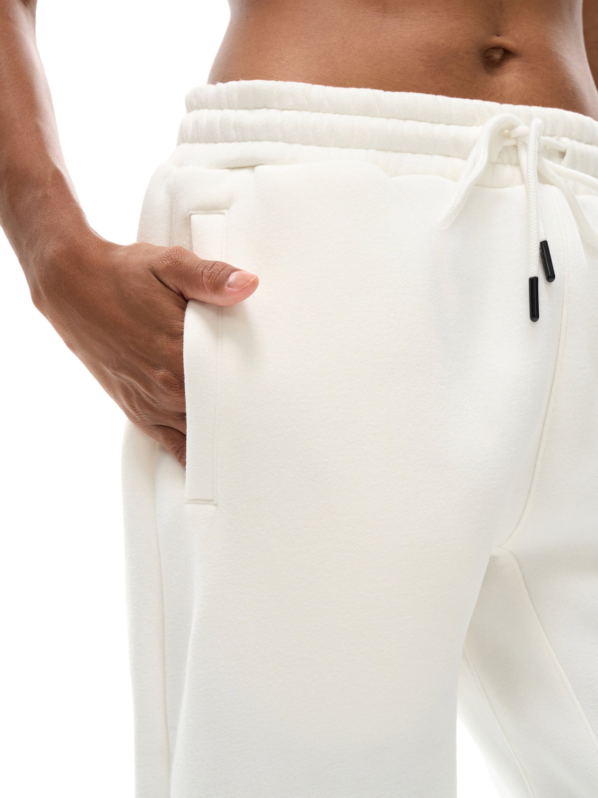 Close-up of unisex heavyweight fleece joggers in white with drawstring waist and hand in pocket