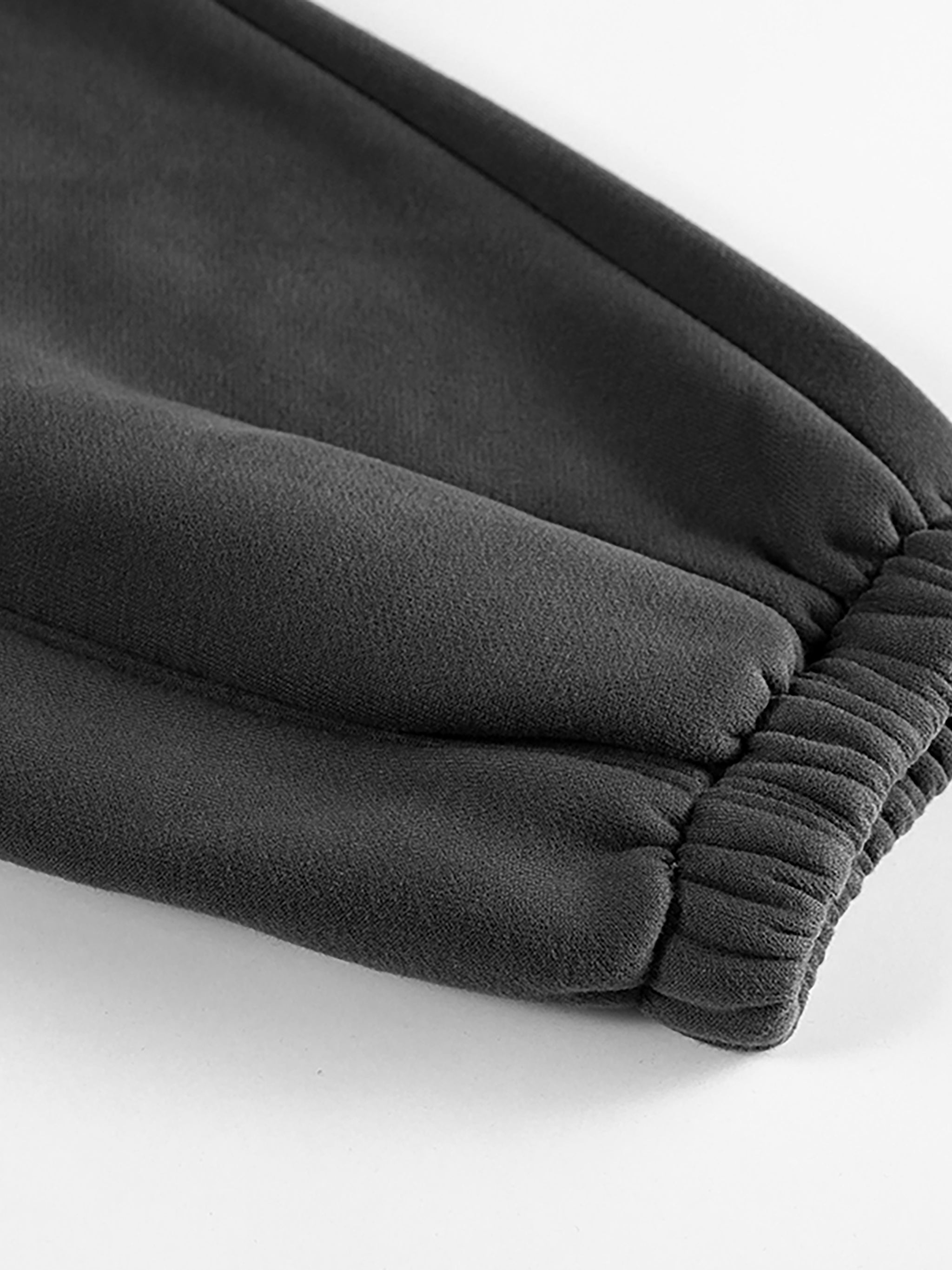 Close-up of black heavyweight fleece joggers with elastic cuff on white background