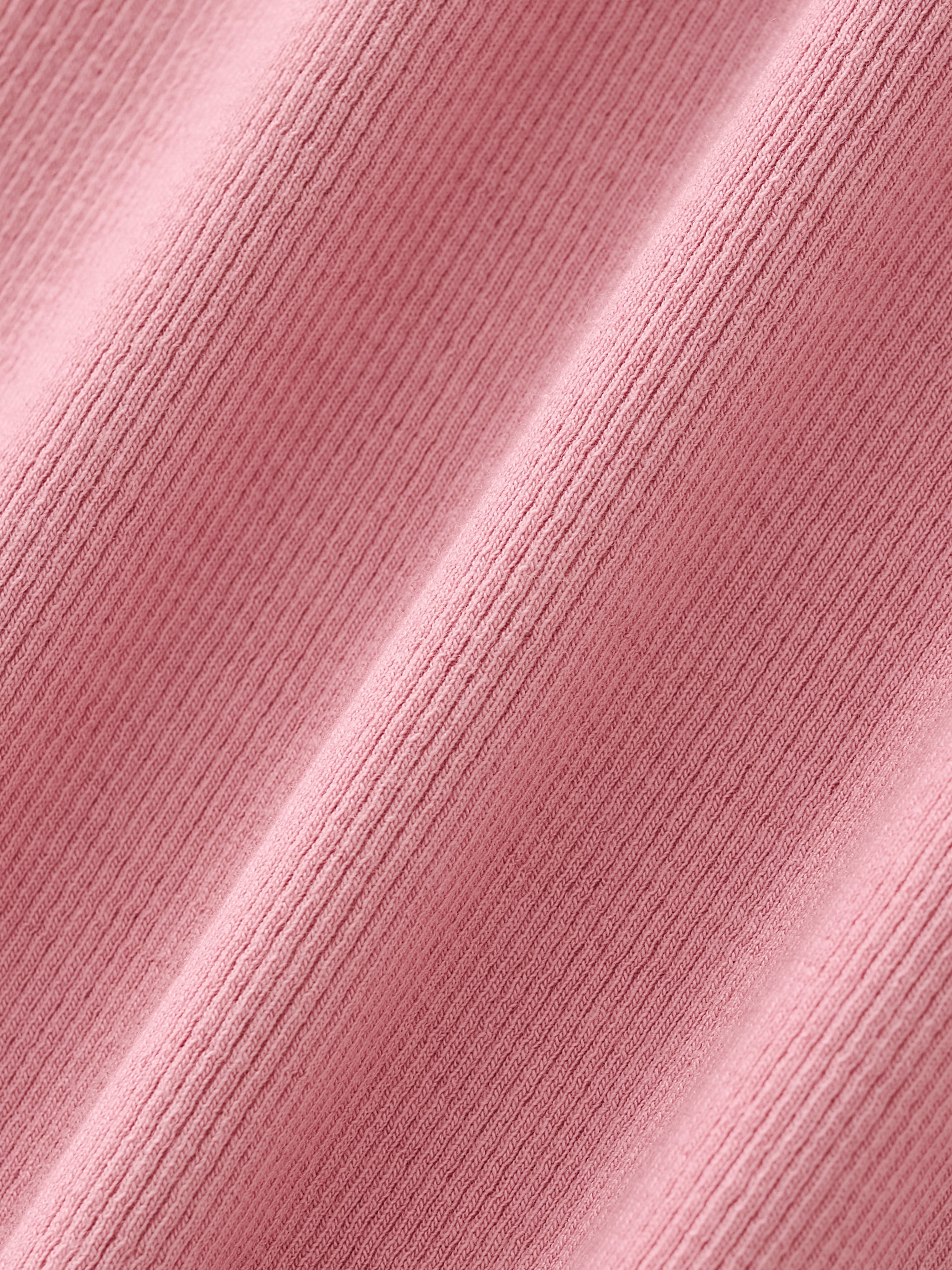Close-up of pink ribbed cotton fabric with soft texture and subtle draping folds