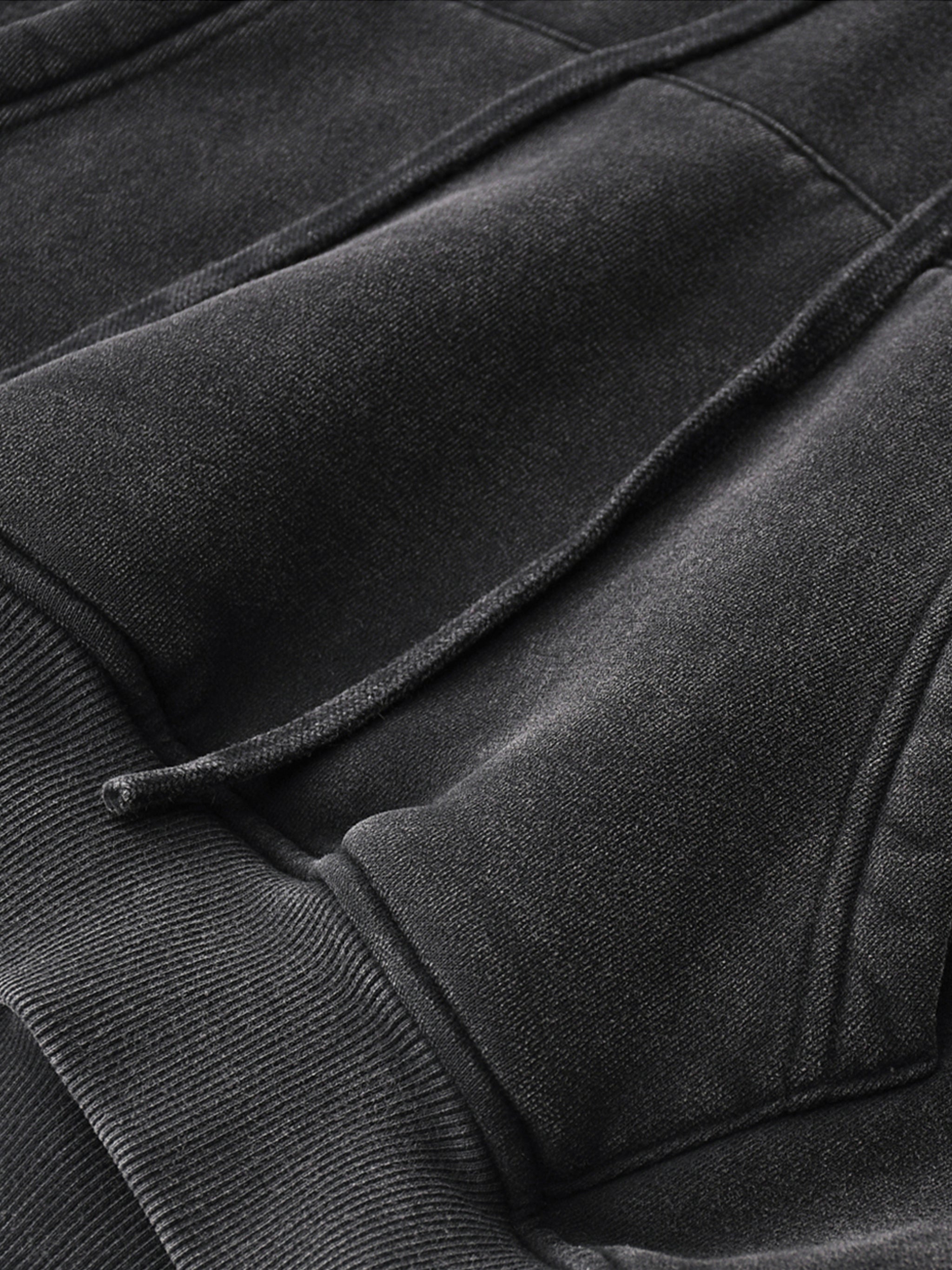 Close-up of a heavyweight, snow-washed cropped hoodie with drawstrings and ribbed hem