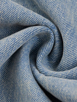 Close-up of light blue sun-fade raw hem denim jeans fabric texture.