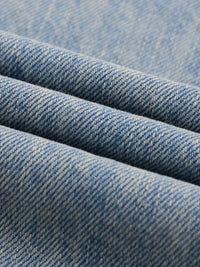 Close-up of sun-faded light blue raw hem denim fabric texture