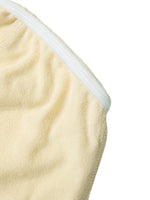 Close-up of a beige women’s cropped tube top with textured fabric and white trim